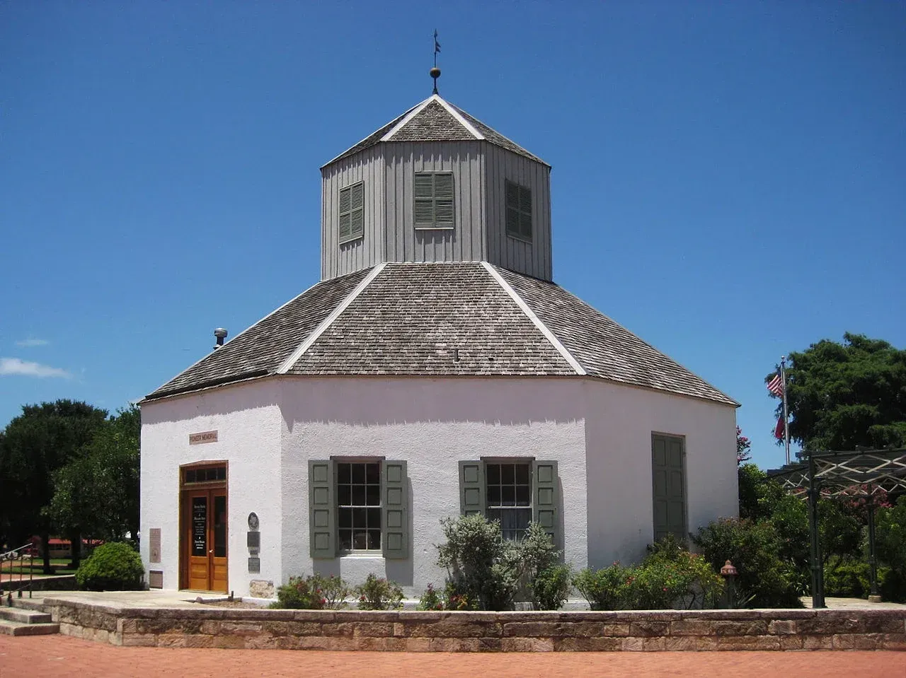 White octagonal building with a tiled roof and small tower under a clear blue sky