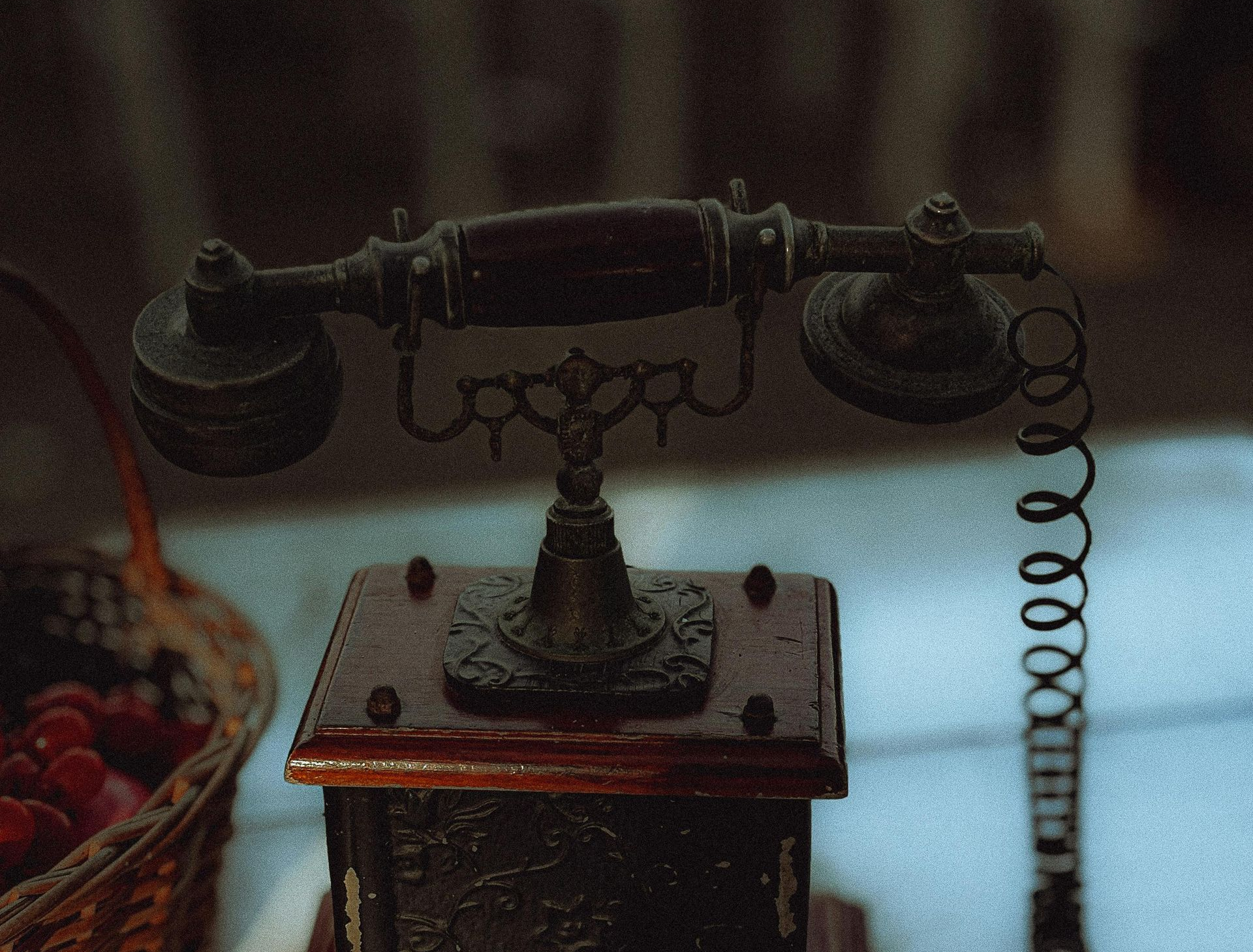 Vintage black rotary telephone on a wooden table in dim light