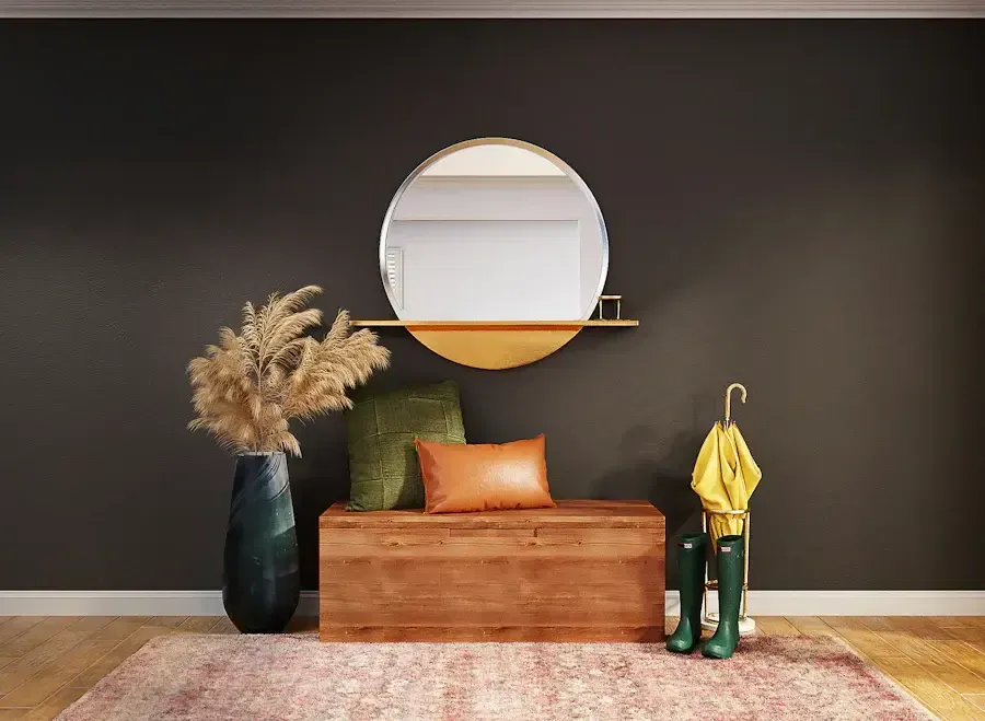 Entryway with dark gray wall, round mirror, wooden chest, and decorative items.