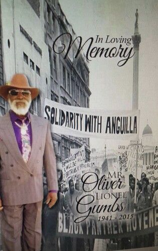 Memorial poster of a man in a hat and suit beside text reading “In Loving Memory” and “Solidarity with Anguilla”