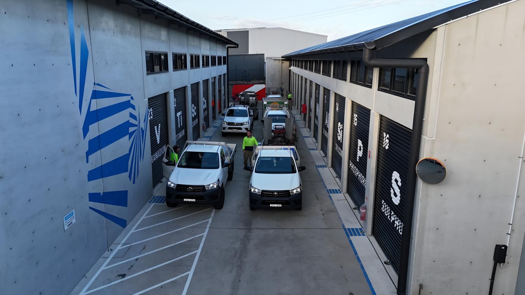 A Row Of White Trucks Are Parked In Front Of A Building — The Local Bloke Lawn & Garden Care In Warners Bay, NSW