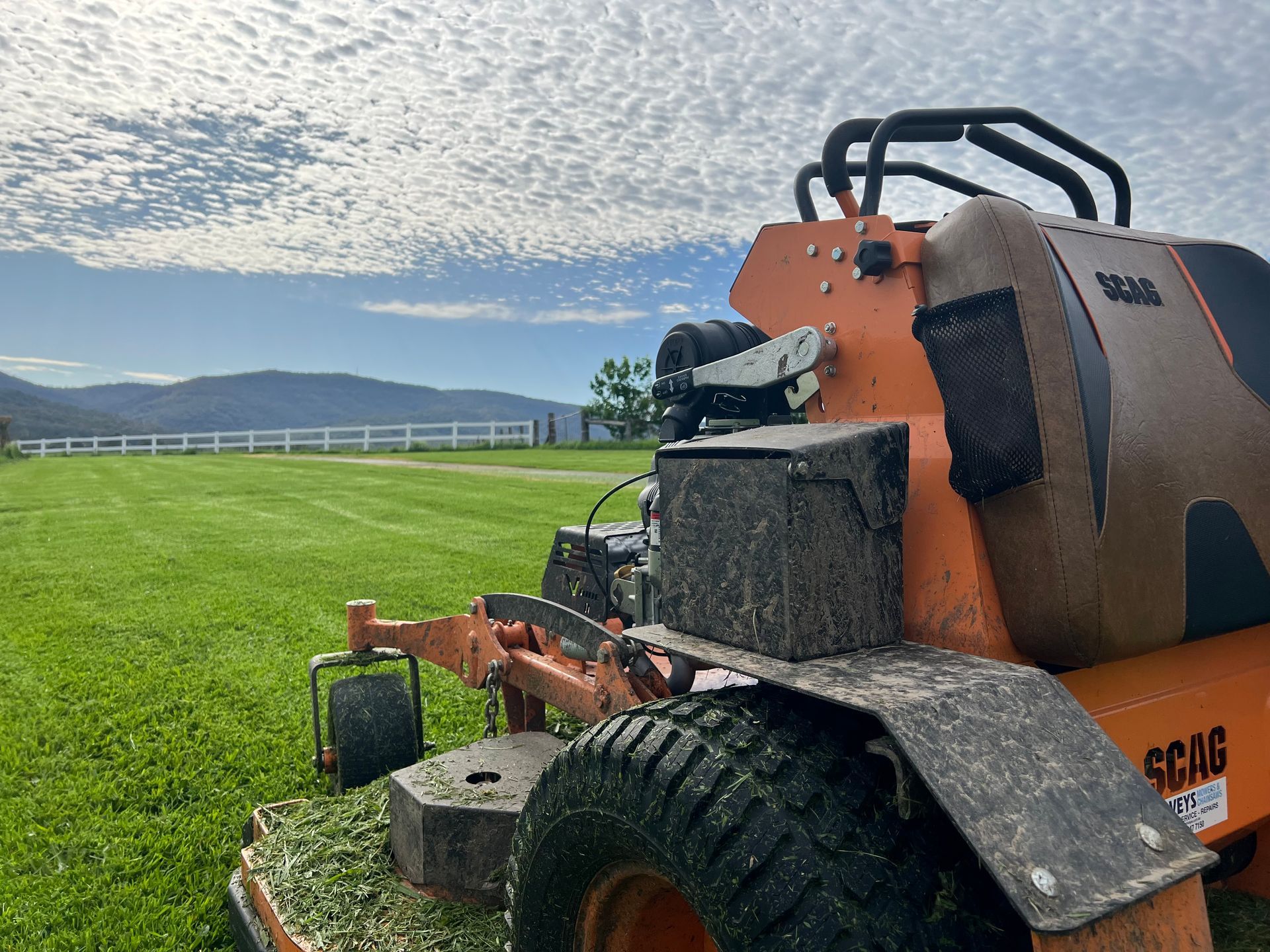 A Green Lawn Mower Is Cutting Grass In A Field — The Local Bloke Lawn & Garden Care In Warners Bay, NSW