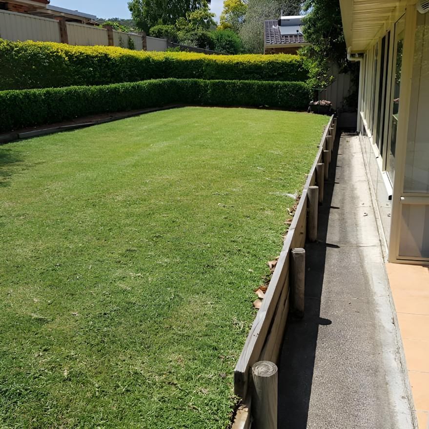 A Lush Green Lawn With A Wooden Fence Surrounding It — The Local Bloke Lawn & Garden Care In Warners Bay, NSW