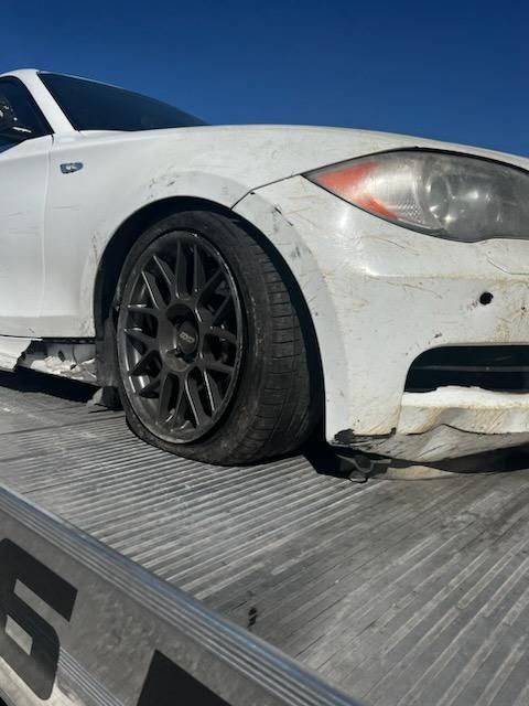 A white car with a flat tire is on a tow truck