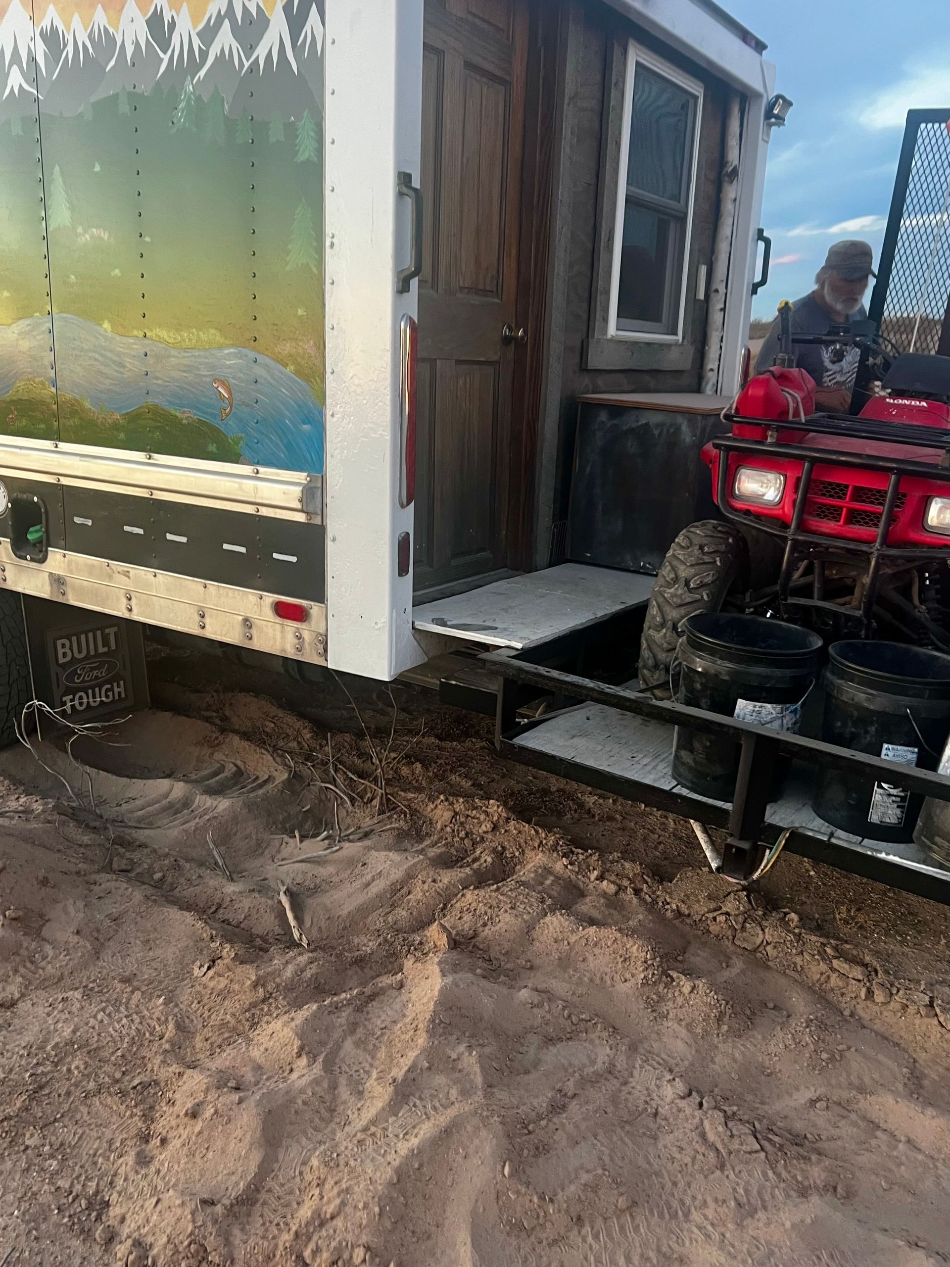 A red atv is parked in front of a trailer.