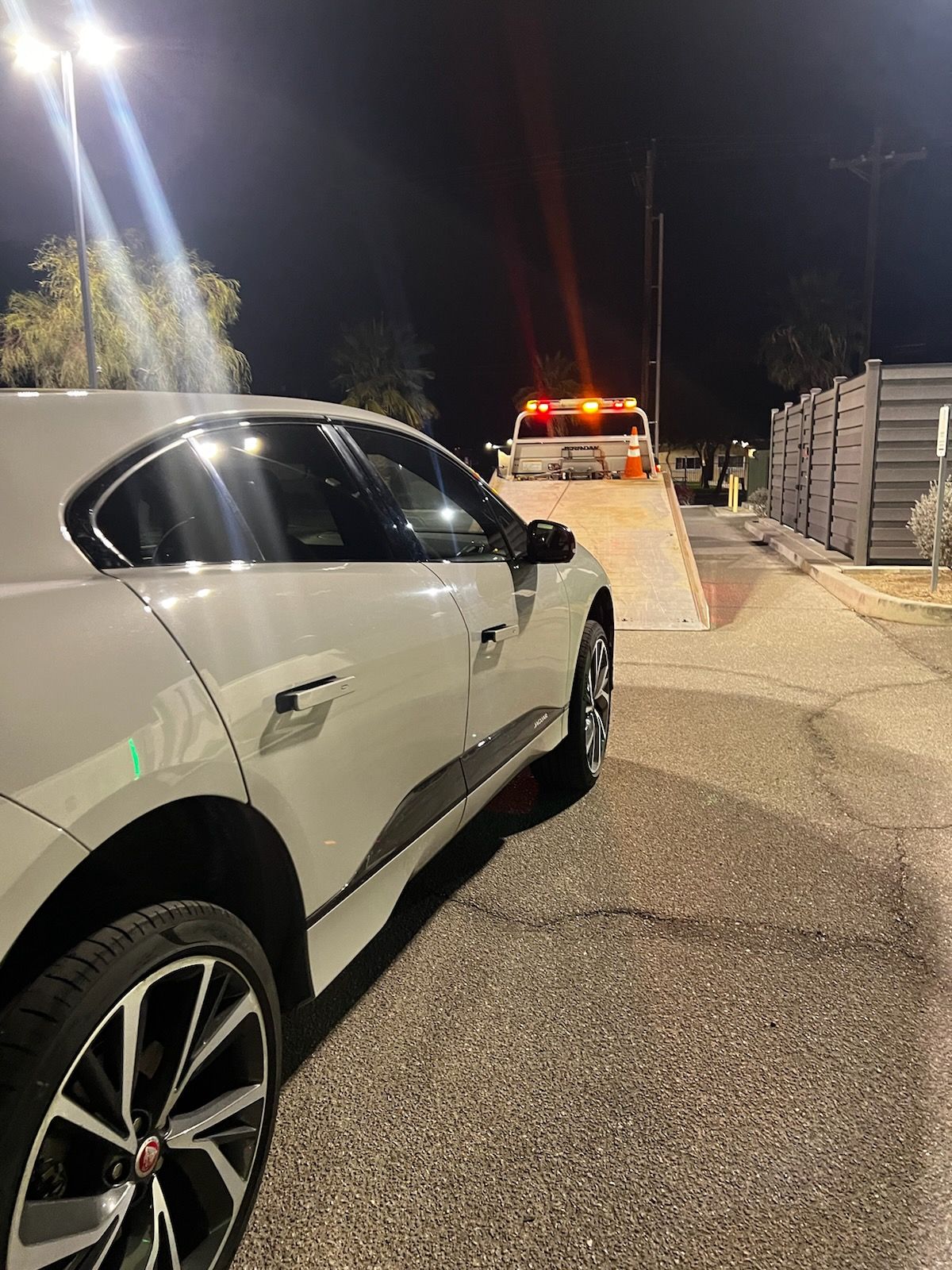 A white car is parked on the side of the road at night.