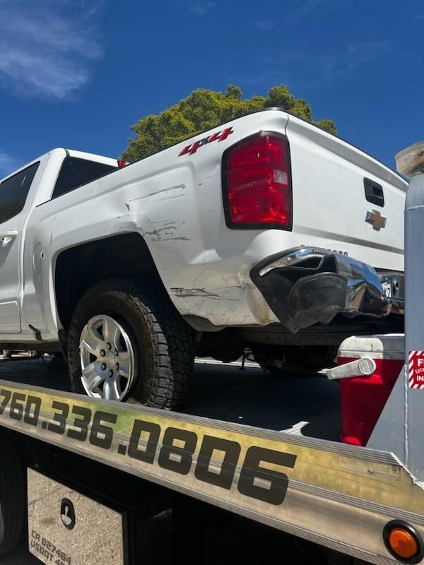 A white truck is sitting on top of a tow truck.