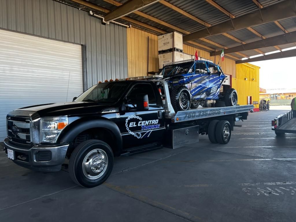A tow truck is carrying a car on the back of it.