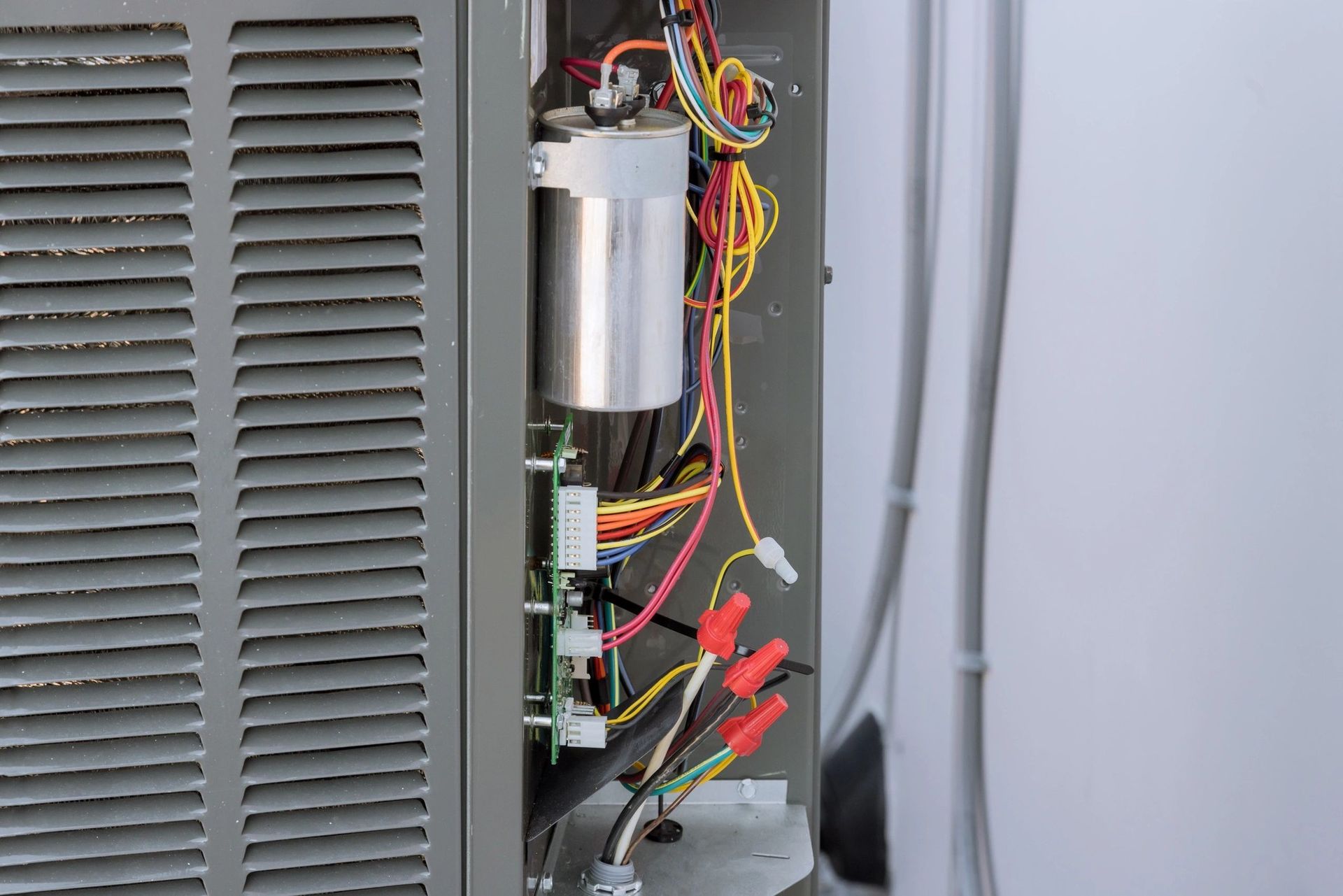 Interior of an air conditioner unit showing wires, a capacitor, and circuit board.