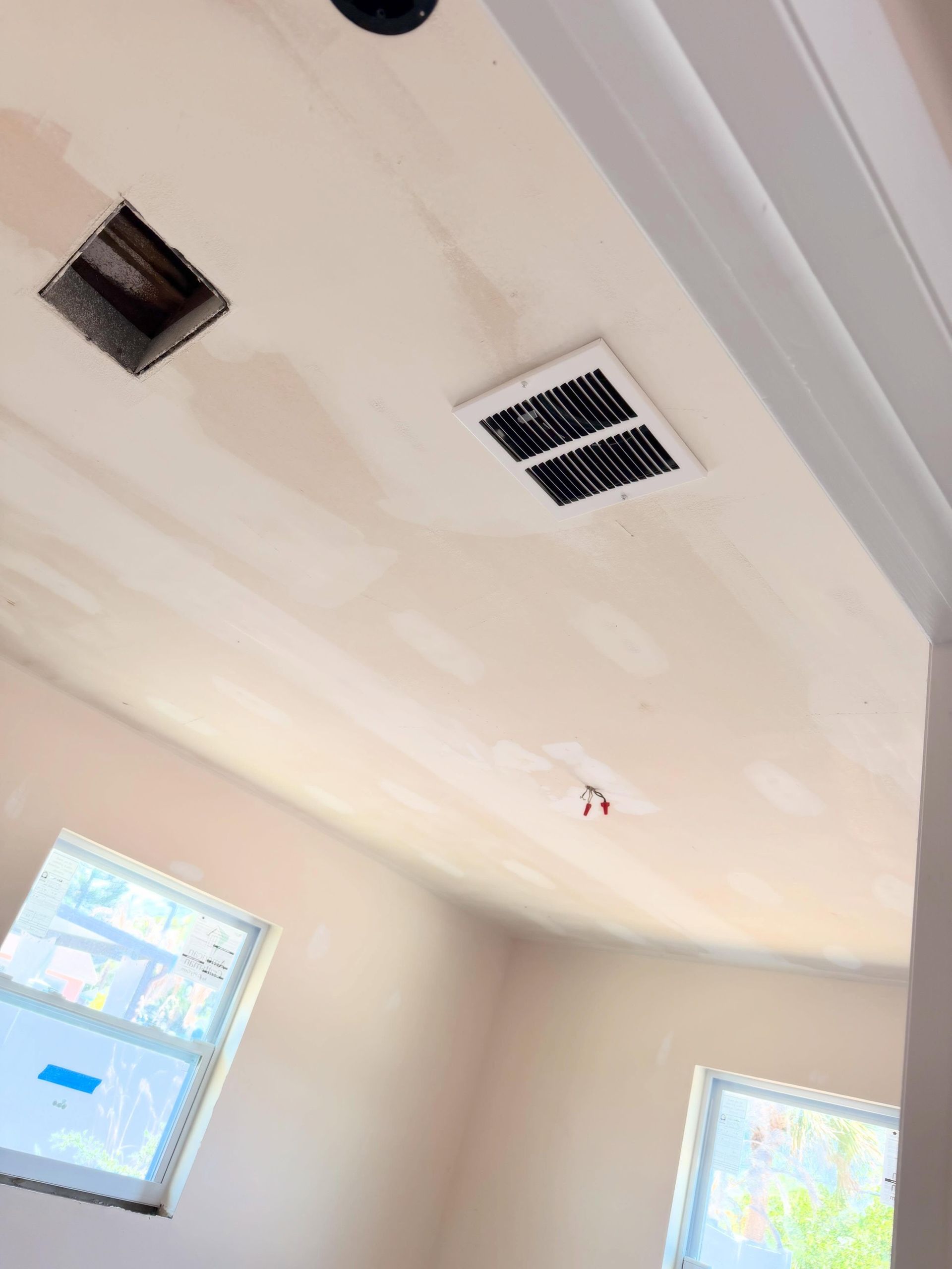 Ceiling with two vents, recessed lights, and a window in a room under renovation