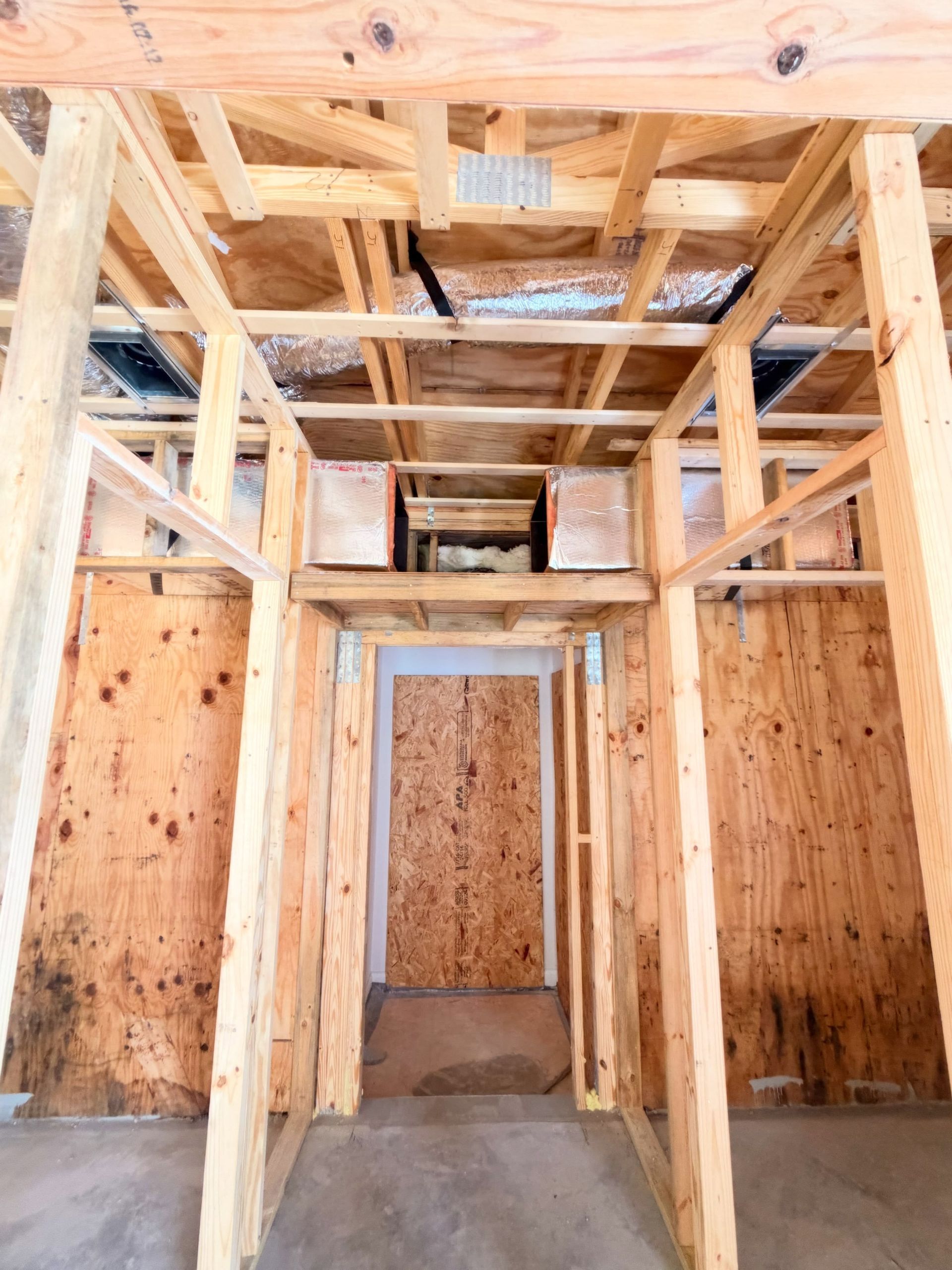 Unfinished wooden interior with exposed framing and a doorway under construction