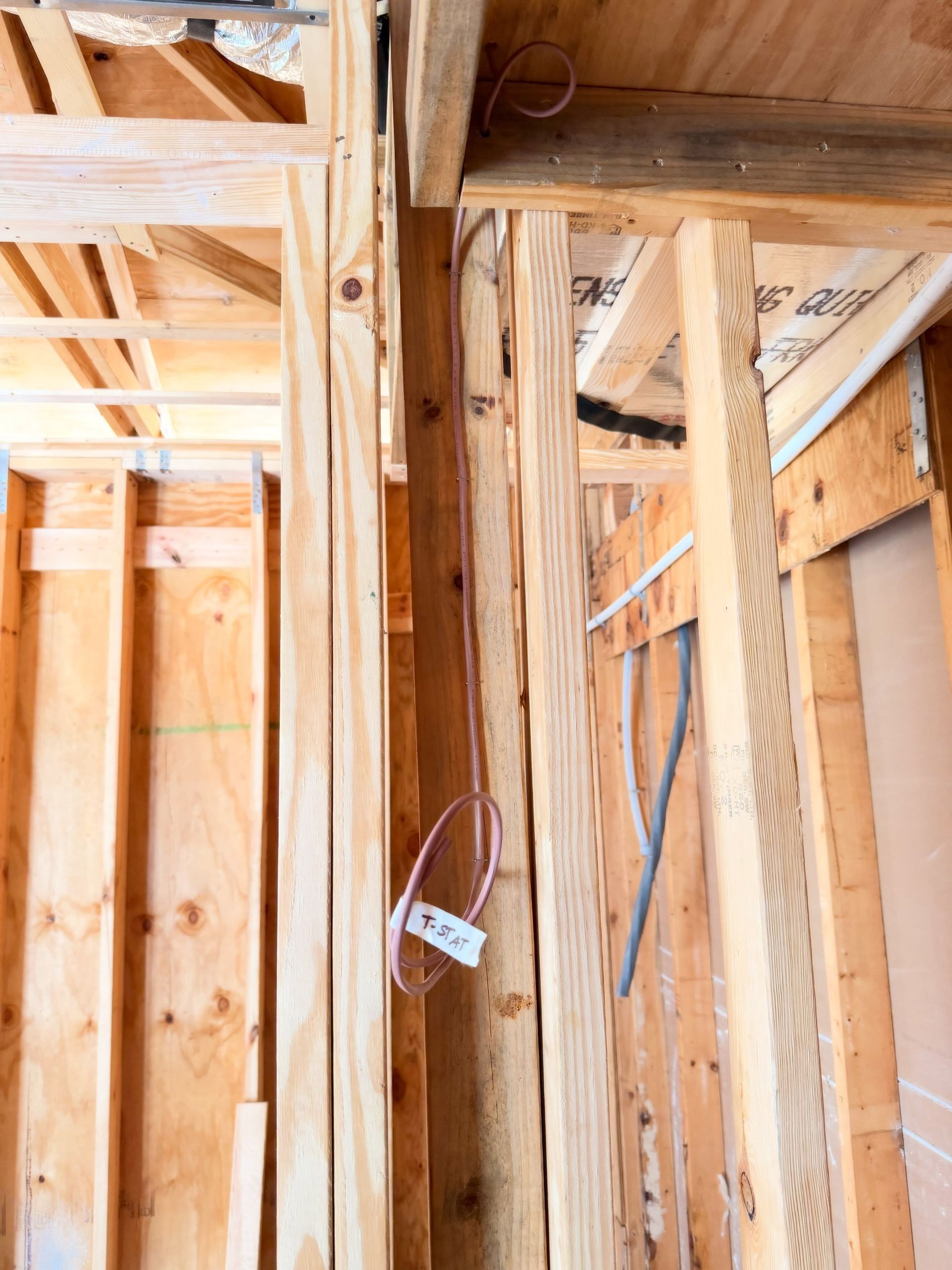Wood-framed interior wall with exposed wiring and insulation in a construction site