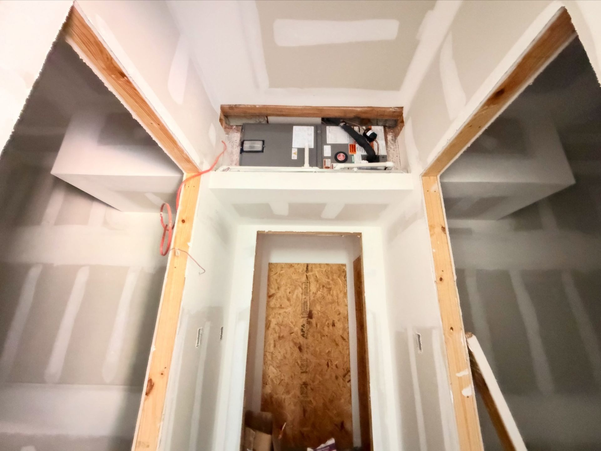 Partially finished room with drywall, exposed wood framing, and a boarded-up doorway under construction