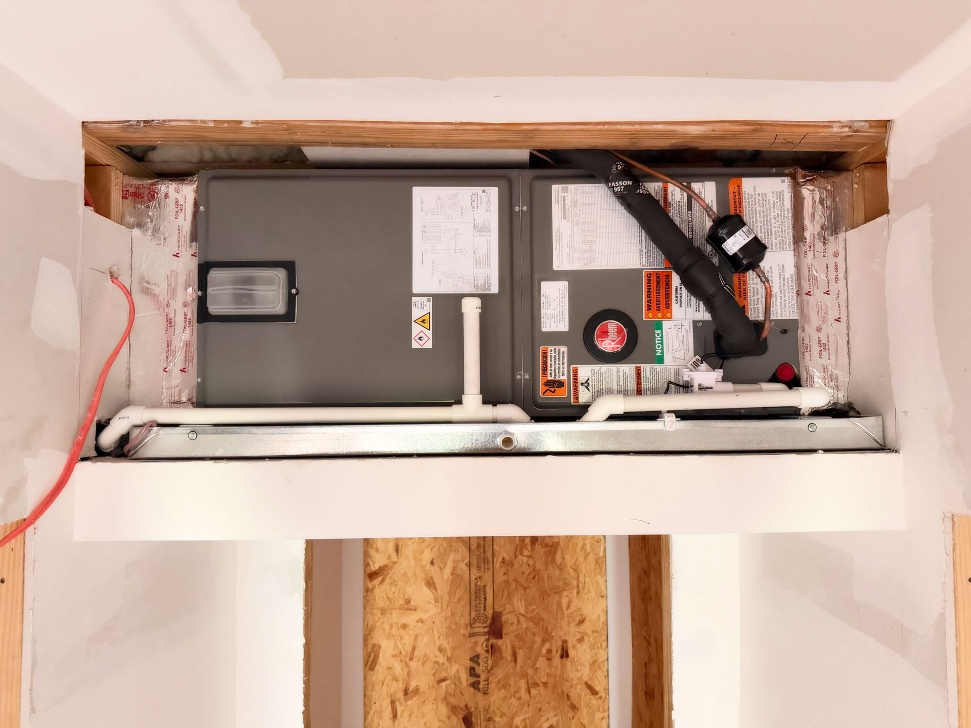 Open ceiling access panel showing HVAC equipment and exposed ducting inside a white room