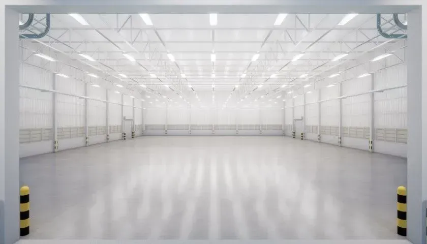 Empty white industrial warehouse with polished floor and bright overhead lighting