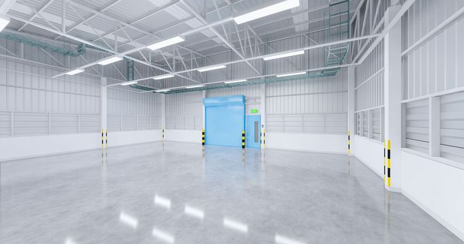 Empty white warehouse interior with polished concrete floor and blue overhead door