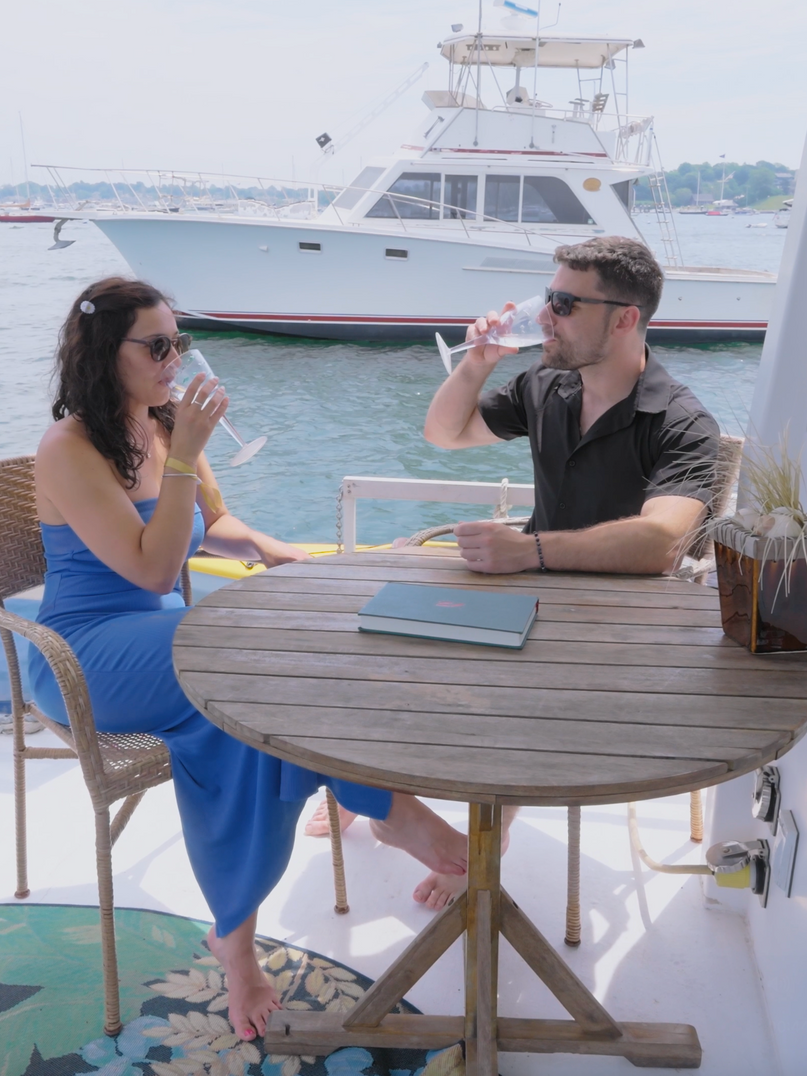 Guests aboard at the table on deck, moored in Newport Harbor