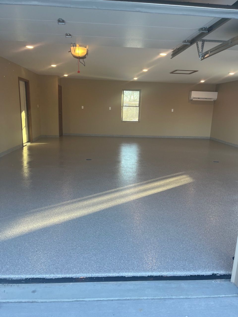 A garage with a concrete floor and a garage door open.