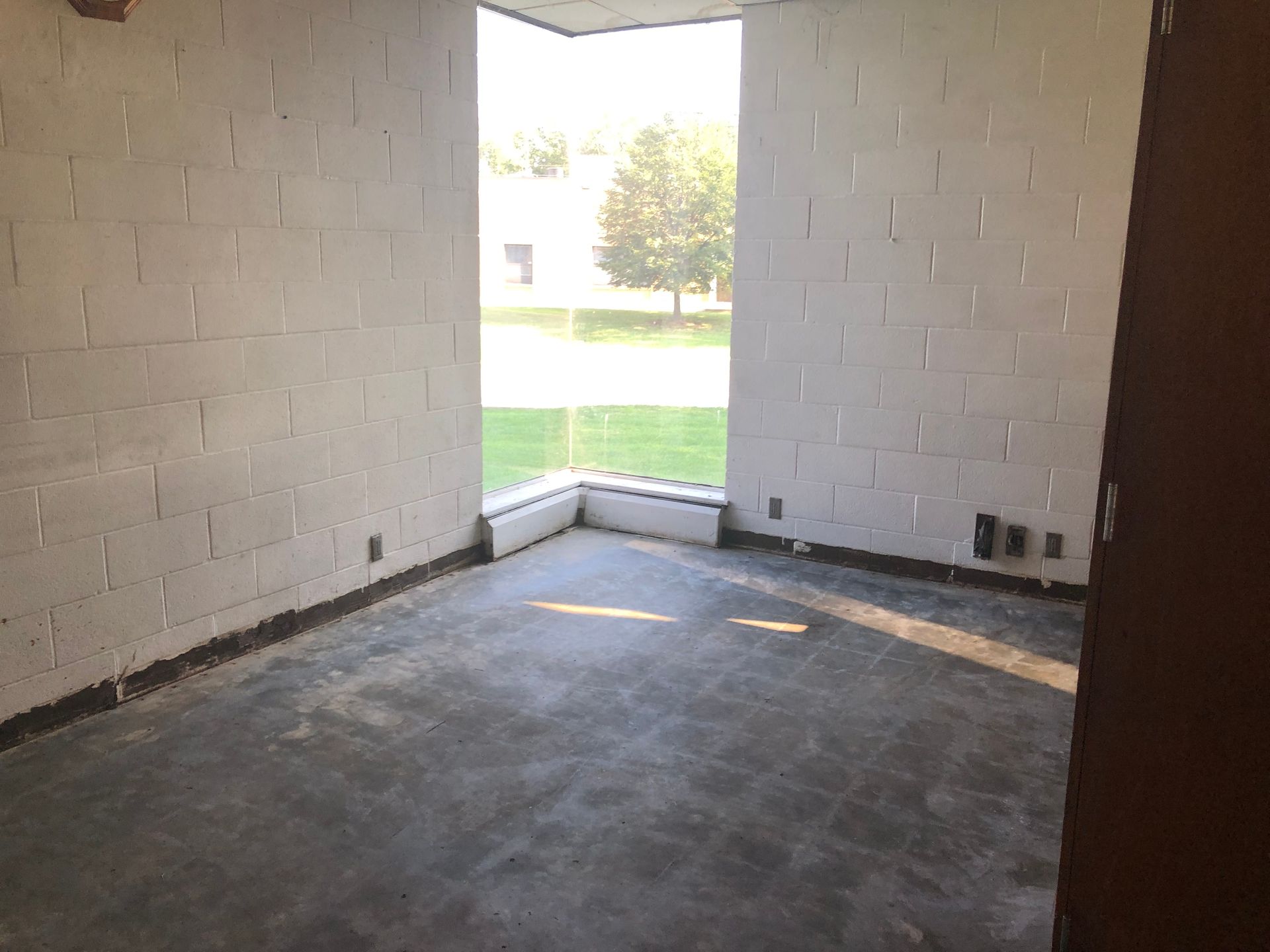 An empty room with white brick walls and a large window.