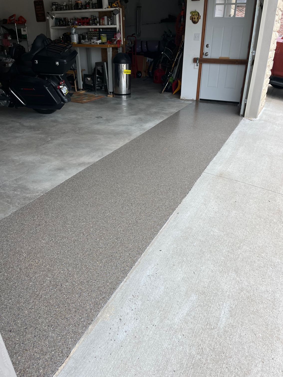 Concrete garage floor with a long gray textured strip running from the foreground to the back wall.