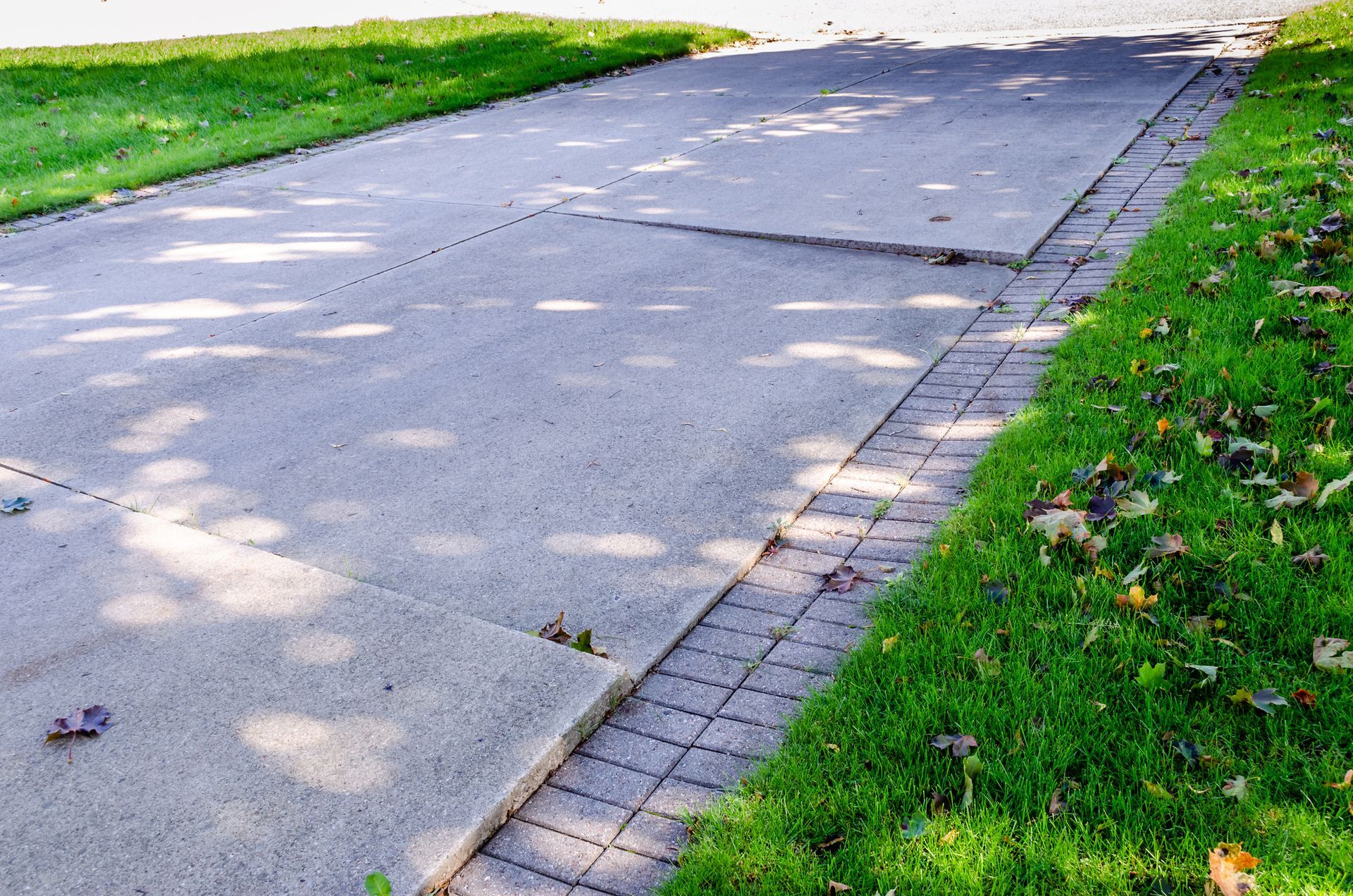 A concrete driveway with grass on the side of it