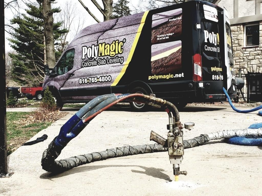 PolyMagic service truck with hoses spraying material on a driveway outdoors