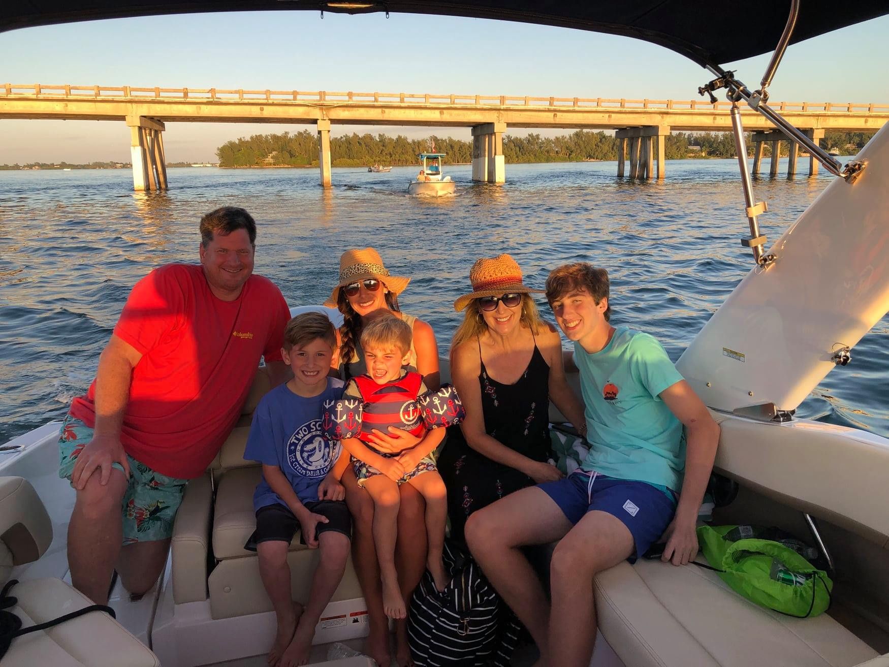 A family is sitting on the boat with a bridge view