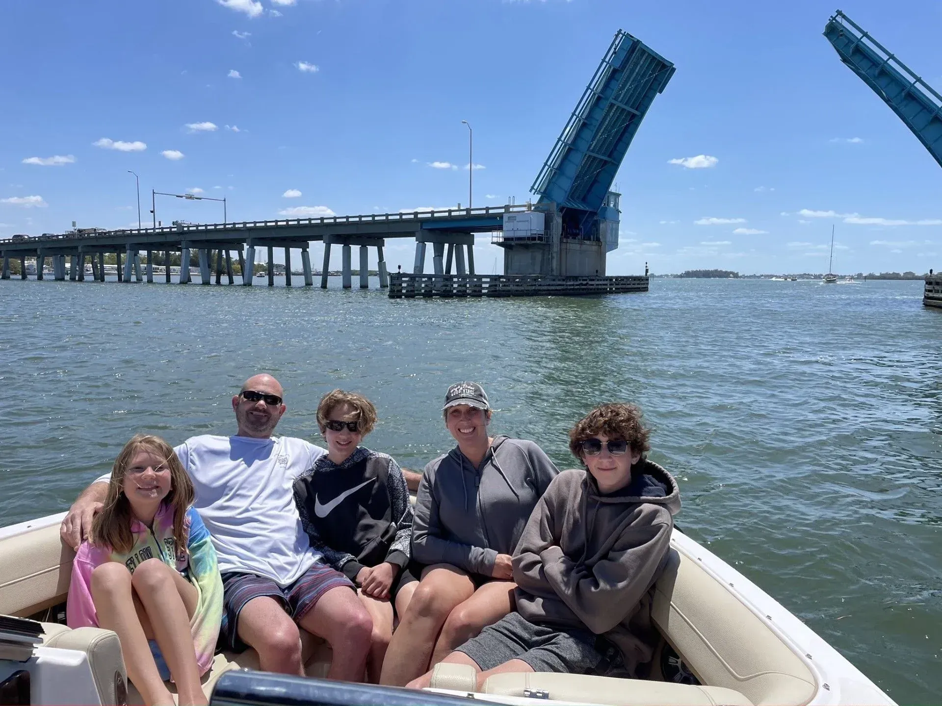 Five people in a boat on the water with a raised drawbridge in the background