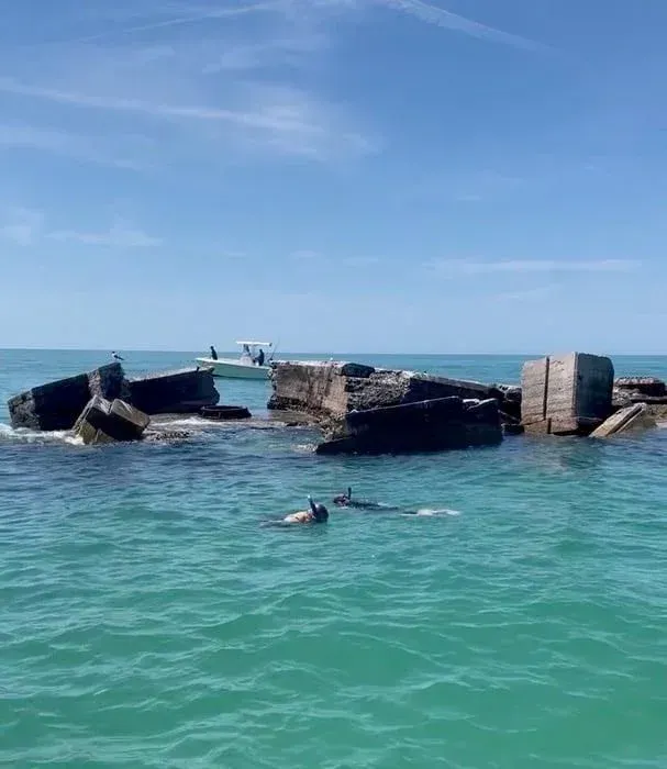 People snorkeling in aqua waters near ruins