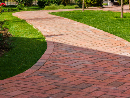 Brick pathway winding through green grass in a garden.