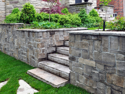 Stone steps ascend between stone walls with planted greenery.