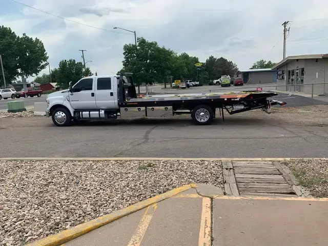 White tow truck on a paved lot; overcast sky.