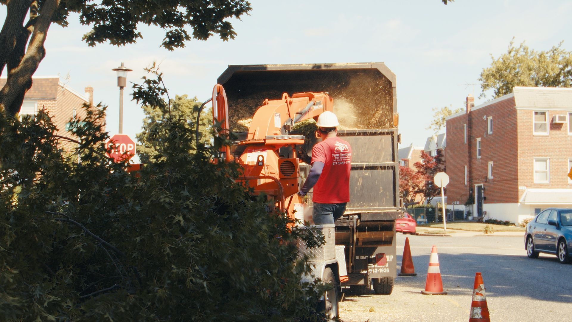 A man in a red shirt is working on a tree chipper