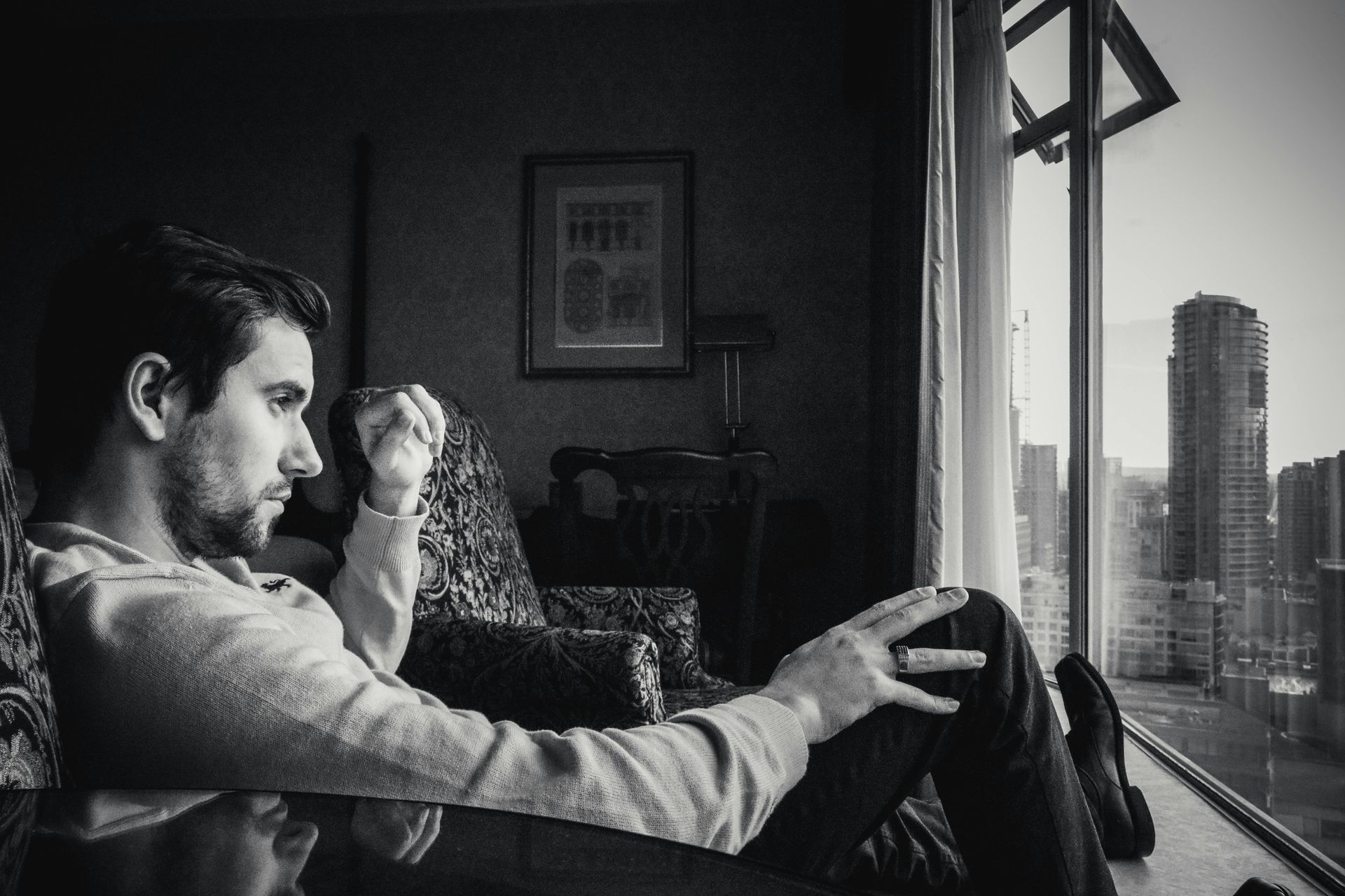 A man is sitting in a chair looking out a window.