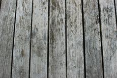 Weathered, grey wooden planks arranged vertically, showing texture and age.