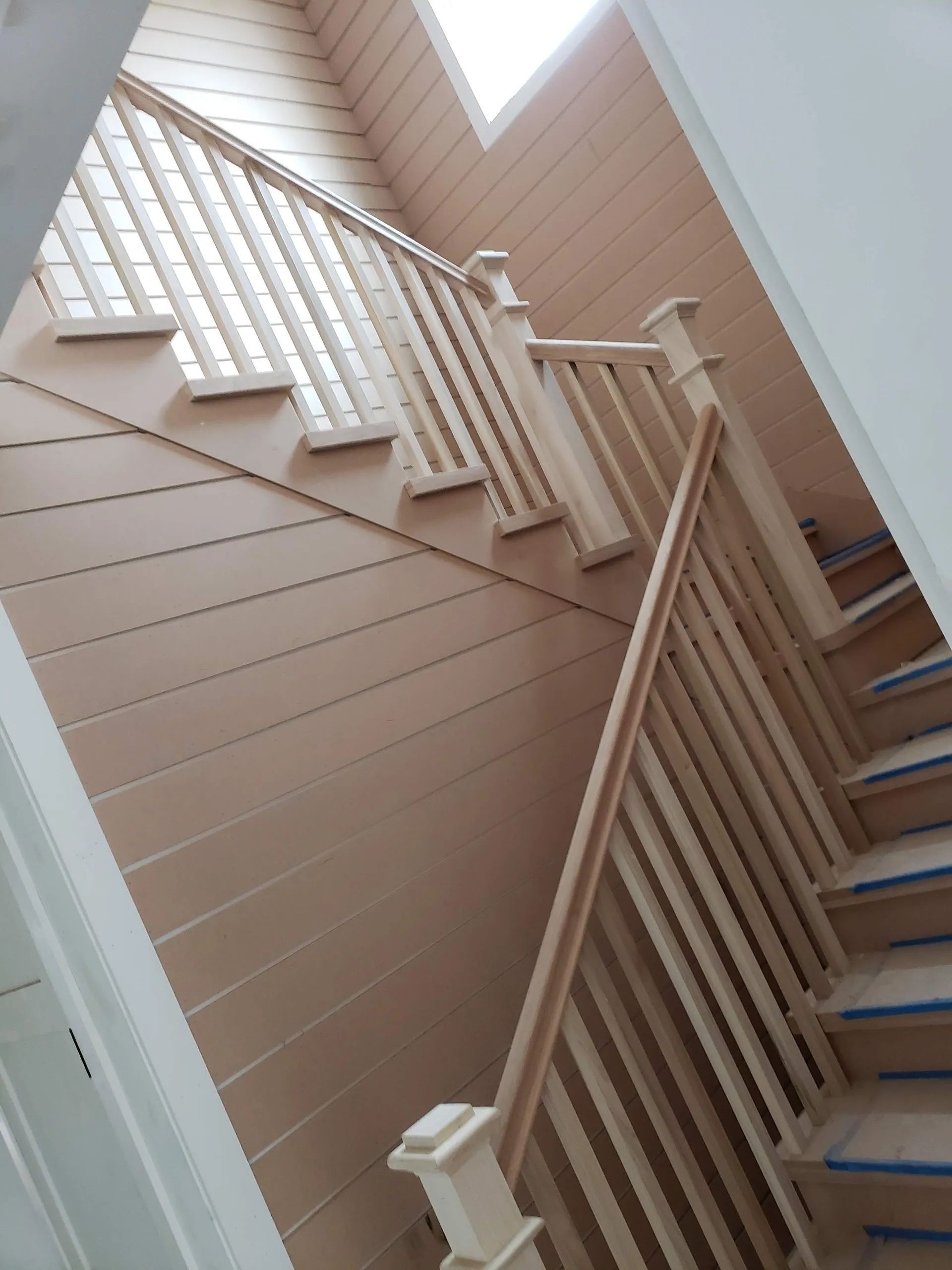 A wooden staircase with a white railing and blue steps