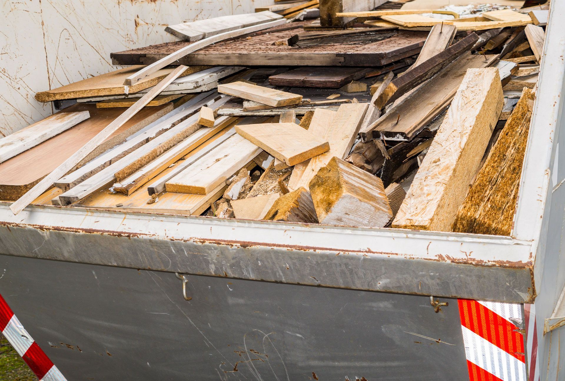 A dumpster filled with wood is sitting on the ground.