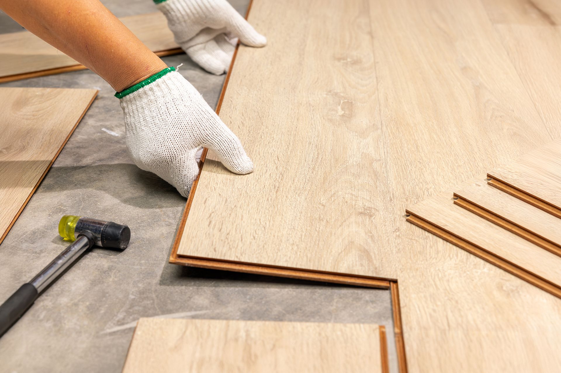 A person is installing a wooden floor with a hammer.