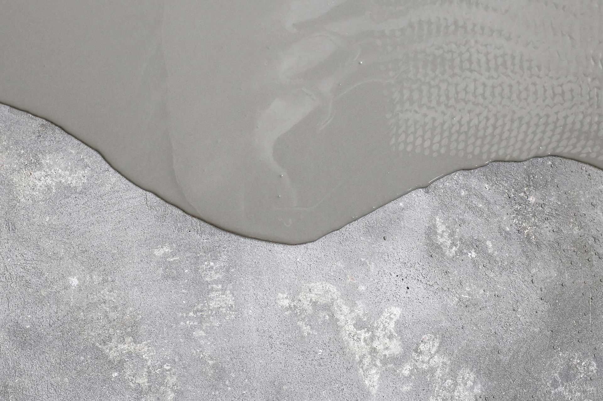 A close up of a concrete surface with a gray liquid coming out of it.