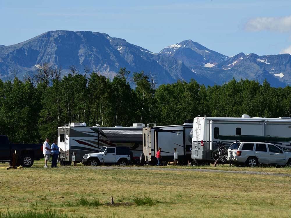 A group of rvs are parked in a field with mountains in the background.