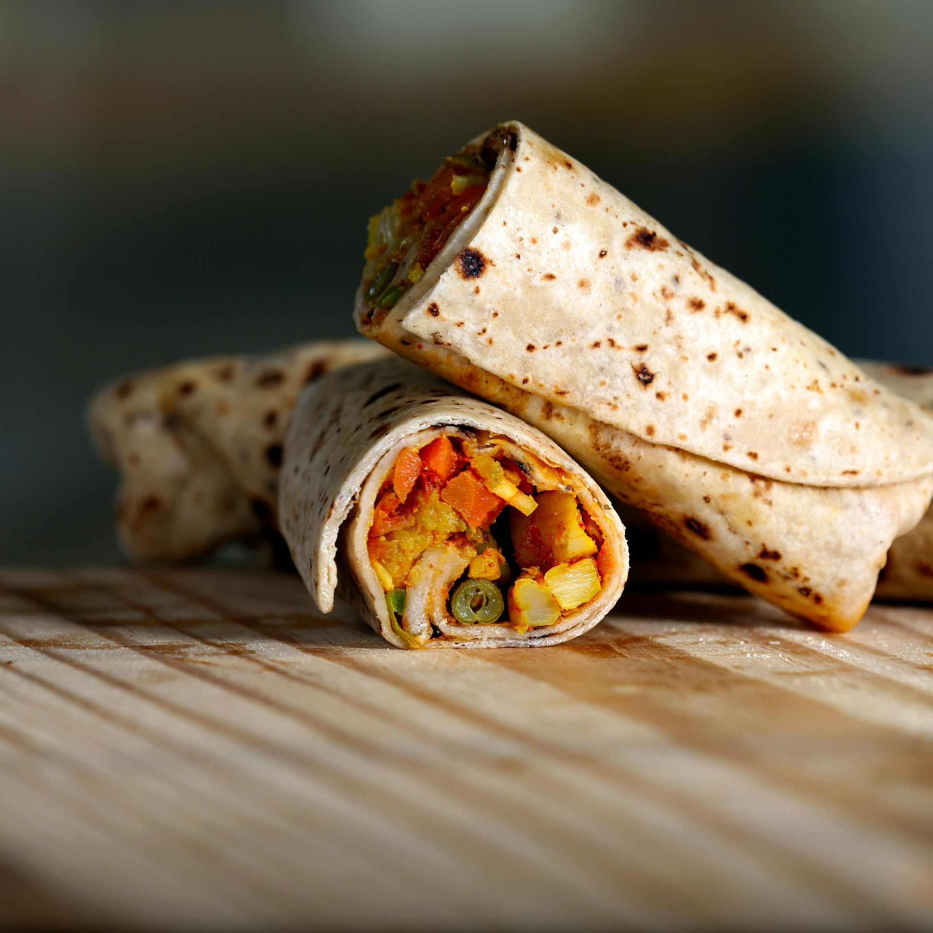 Two tortilla wraps are stacked on top of each other on a wooden table.