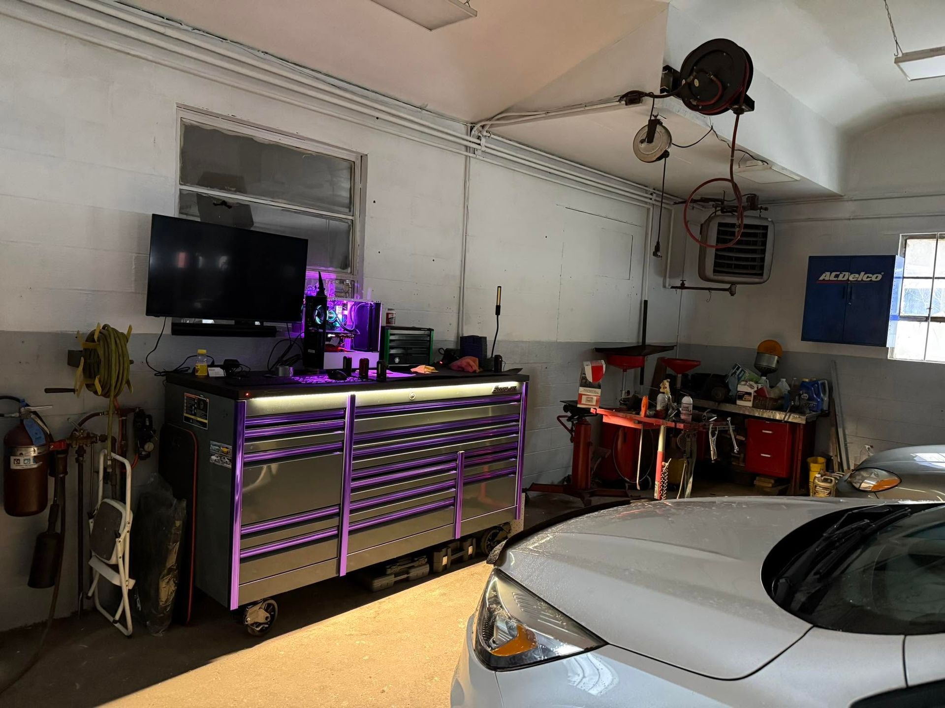 Garage workspace with tool cabinets, purple LED lighting, and a white car in the foreground