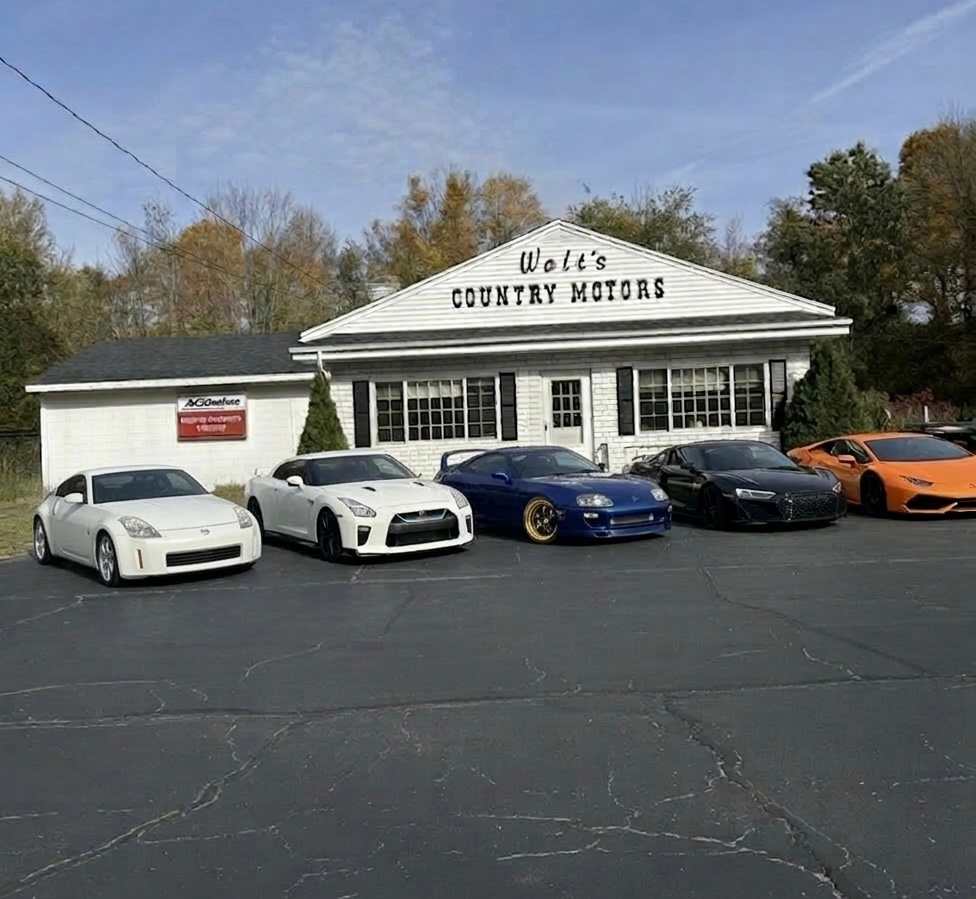 Five sports cars parked outside Walt’s Country Motors on a sunny day.
