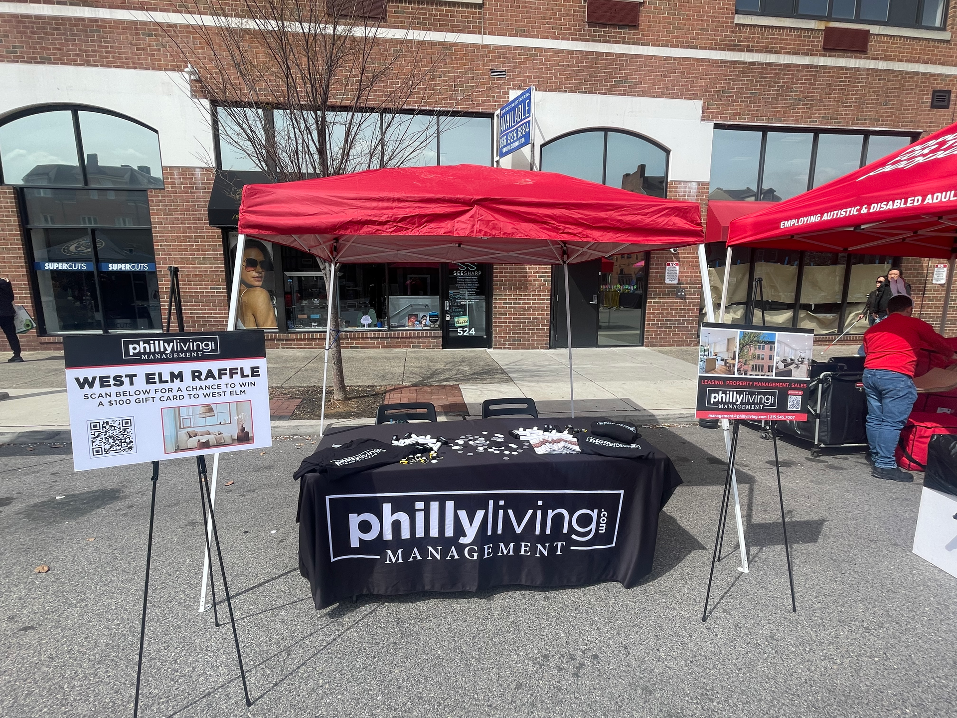A table with a philly living sign on it is in front of a building.