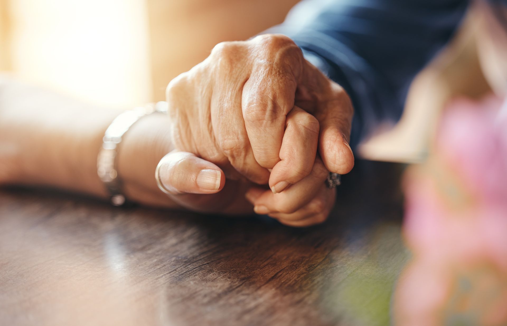 Two hands clasped together, possibly offering comfort or connection.