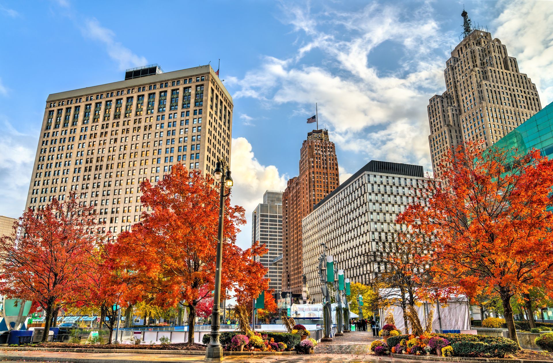 Autumn city park with red-orange trees and tall downtown buildings under a blue sky Autumn city park with red-orange trees and tall downtown buildings under a blue sky