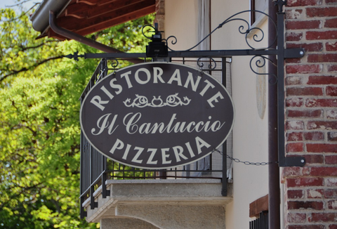 Oval sign reading “Ristorante Il Cartuccio Pizzeria” on a brick building balcony.