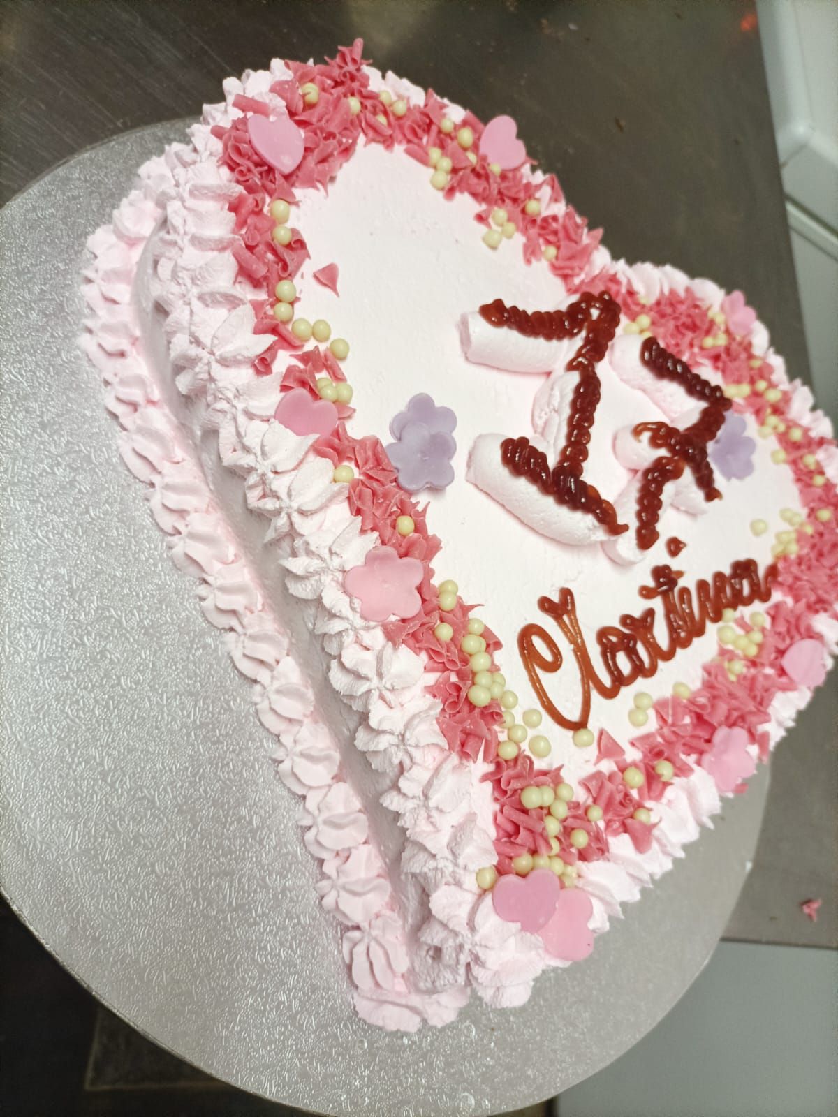 Torta bianca a forma di cuore con glassa rosa, il numero