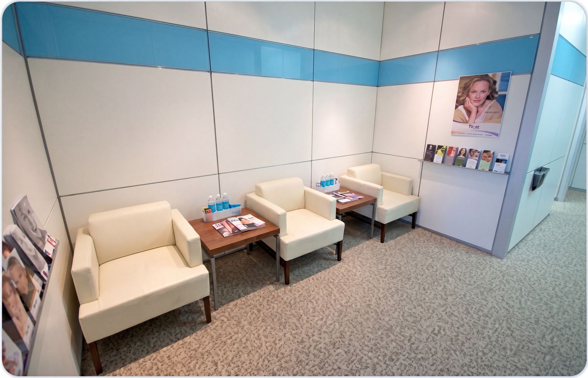 Small waiting room with beige chairs, a side table, and a wall display in a clinic or office.