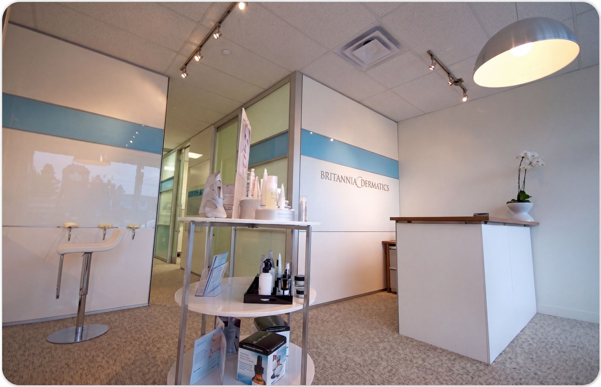 Modern spa reception with white desk, product display, and blue accent wall